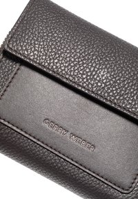 Brun læderpung med en struktureret overflade, der har en frontlåg og præget mærkenavn "GERRY WEBER" nederst.