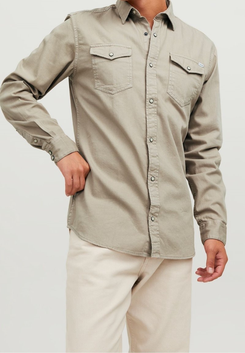 Beige lange mouwen shirt met een button-down kraag, twee borstzakken en drukknoopsluiting. Zachte katoenen stof, ontspannen pasvorm en afgeronde zoom.