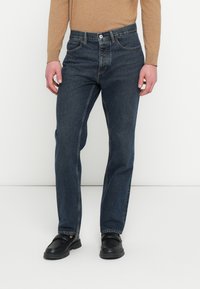 Sötétkék farmernadrág egyenes szárú szabással, gomb- és cipzárzáródással, ötpocketes kialakítással és minimális kifakulással.