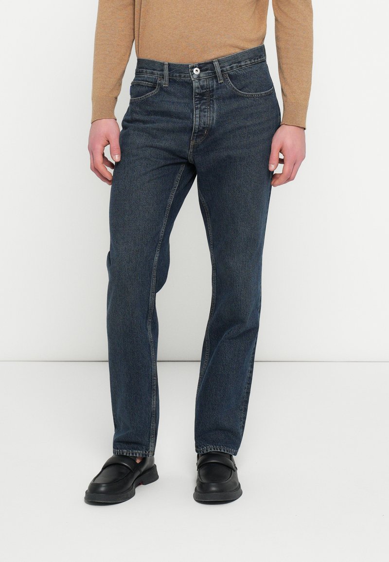 Sötétkék farmernadrág egyenes szárú szabással, gomb- és cipzárzáródással, ötpocketes kialakítással és minimális kifakulással.