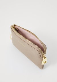 Beige leather pouch with a textured surface, gold zipper, and hardware. Interior is light pink. Compact design with a keyring attachment.