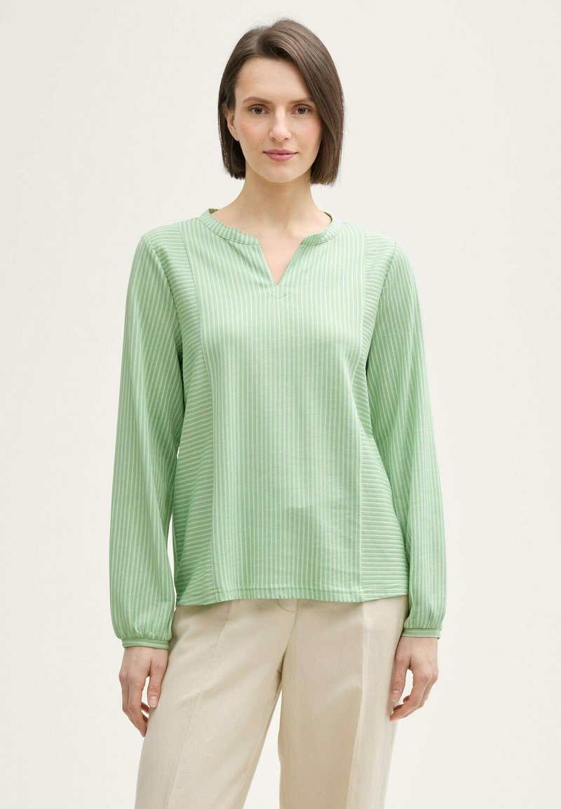 Blouse verte à manches longues avec un col en V, ornée de rayures verticales dans des nuances variées de vert, fabriquée en tissu léger.