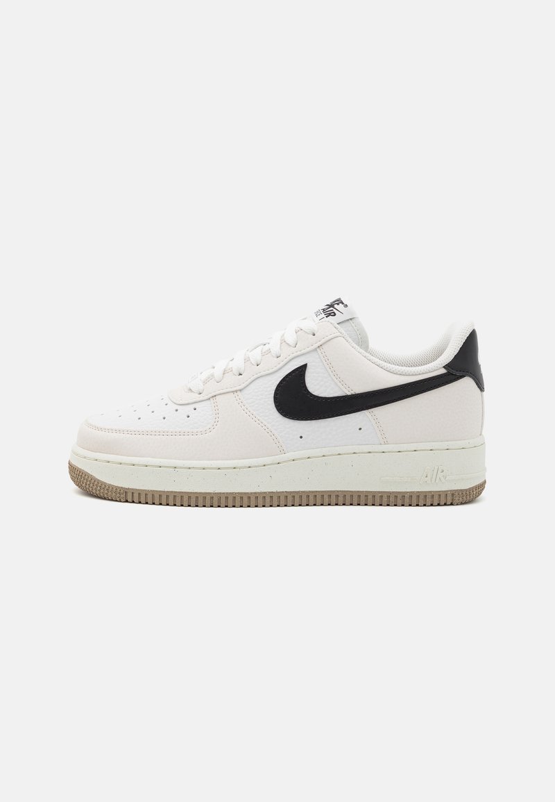 Zapatilla Nike Air Force 1 de cuero blanco con swoosh negro, paneles texturizados, puntera redondeada, cordones blancos y suela de goma.