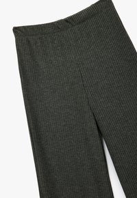 Dunkelgrüne gerippte Leggings mit einem elastischen Bund, die ein gerades Bein-Design und eine weiche Stofftextur aufweisen.