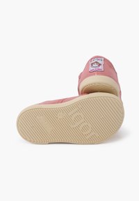 Scarpe di tela rosa con una suola in gomma crema, caratterizzate da un'etichetta cucita con un design di scimmia, una superficie testurizzata per una presa migliore e una forma semplice e arrotondata.