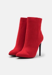 Punaiset tekoturkiskuosiset nilkkurit, joissa on terävä kärki, korkea stiletto-korko ja saumaton muotoilu, ja jotka omaavat sileän tekstuuripinnan.