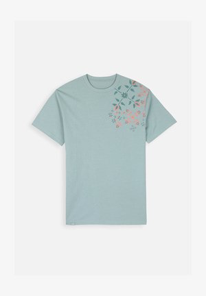 T-shirt en coton bleu clair à manches courtes avec un imprimé floral rose et vert foncé, concentré sur le côté supérieur gauche.