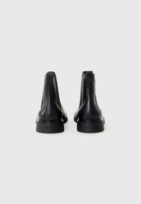 Black leather ankle boots with a textured finish, a rounded toe, and a flat rubber sole. Features elastic side panels for flexibility.
