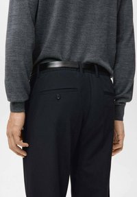 Pantaloni da uomo blu scuro con una texture liscia, cintura nera e dettaglio con bottone sulle tasche posteriori. Maglia grigia a maniche lunghe visibile.