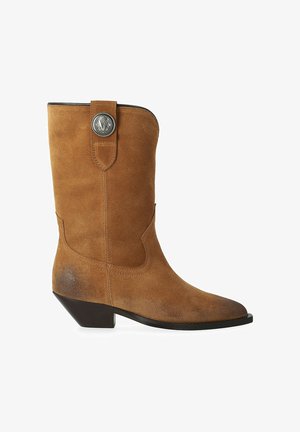 Botte de cow-boy en daim couleur fauve mi-mollet avec un bout pointu, un talon noir incliné bas et un bouton décoratif argenté sur la sangle de traction.