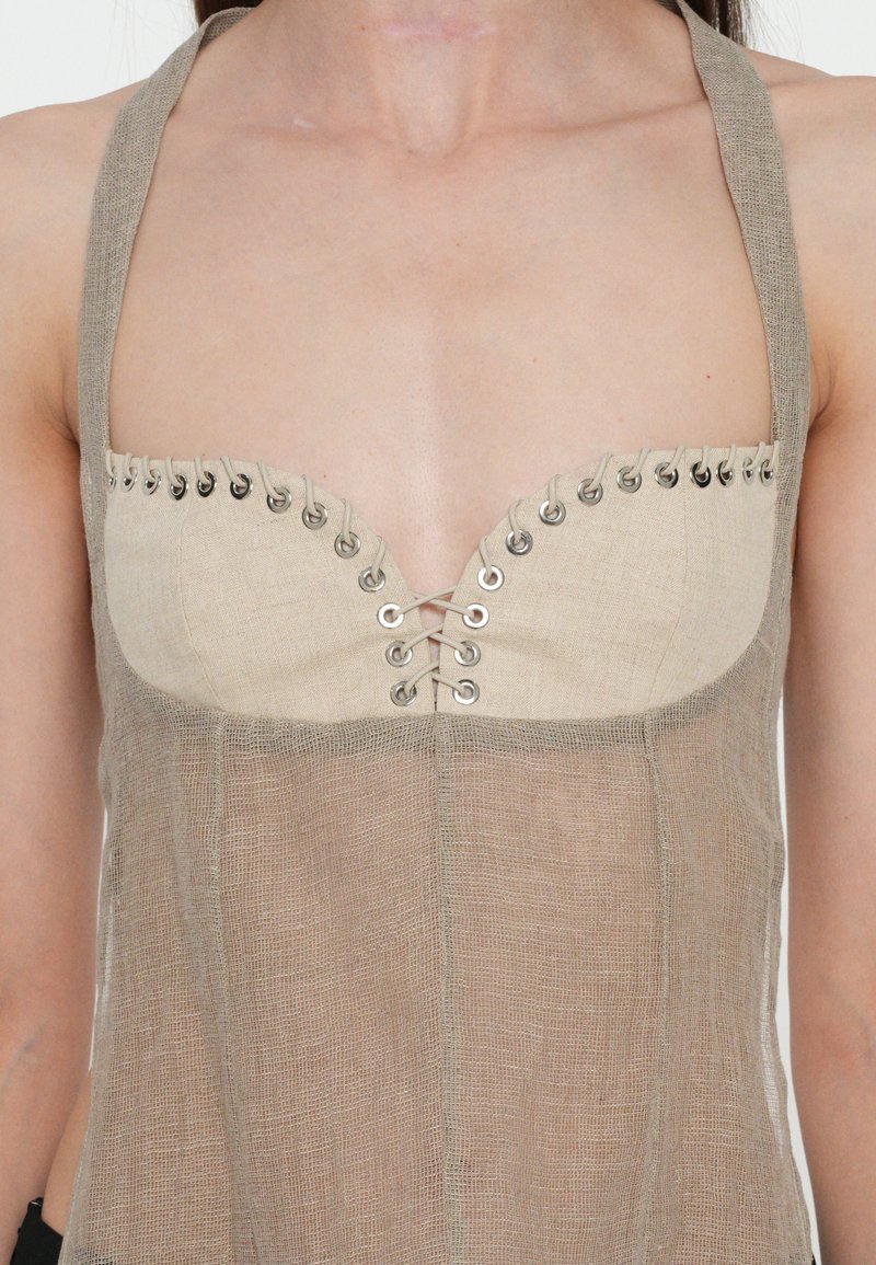 Beige linen top with a fitted bodice, featuring metal eyelets and lace-up detail. Sheer fabric with wide straps creates a lightweight design.