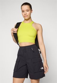 Ljusgrön kort topp med skuren axeldesign, matchad med svarta cargoshorts som har två framfickor och logodetalj.