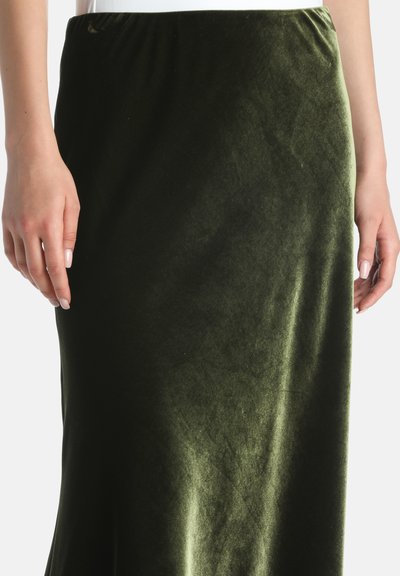 Zelena suknja od somota s glatkom teksturom, s uskim pojasom. Tkanina ima blagi reflektirajući sjaj.