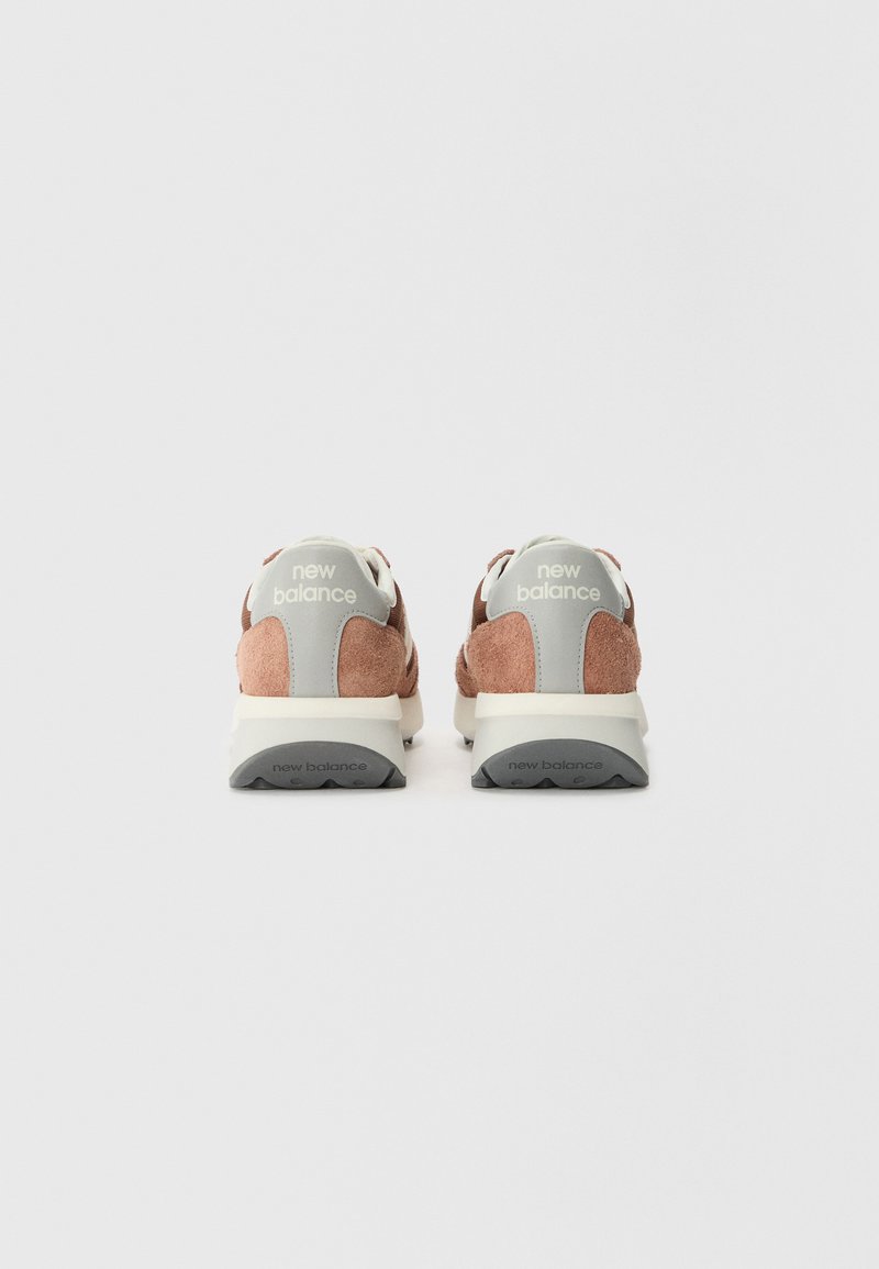 Baskets en daim rose avec des accents gris et une semelle blanche, dotées d'un talon rembourré et d'un logo à l'arrière.