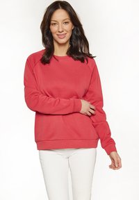 Koraal sweatshirt met raglanmouwen, geribbelde manchetten en zoom, gemaakt van zachte stof. Draag het met witte broek, met een losse pasvorm.