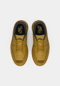 Nike Air tenisice u senfu žutoj boji s perforiranim prstom, sivi akcenti i usklađene vezice. Imaju podstavljeni đon i logo na ulošcima.