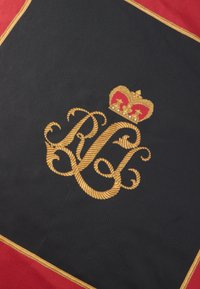 Fekete textil, arany hímzett "RC" kezdőbetűkkel, koronával és piros díszítéssel, arany kerettel keretezve.