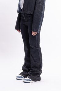 Musta farkkutakki ja levenevät housut, joissa on näkyvät ompeluyksityiskohdat. Yhdistettyinä sinisten yksityiskohtien omaaviin valkoisiin lenkkitossuihin.