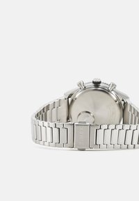 Orologio da polso in acciaio inox argentato con finitura spazzolata e lucida, caratterizzato da una cassa rotonda, bracciale a maglie metalliche e una corona.