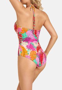 Kolorowy jednoczęściowy strój kąpielowy z tropikalnym wzorem liści w odcieniach różu, pomarańczu i zieleni. Wykonany z teksturowanej tkaniny z wiązaniem na szyi.