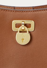 Brown leather handbag featuring a gold-toned padlock closure with engraved logo and rectangular hardware detail. Smooth texture, structured design.