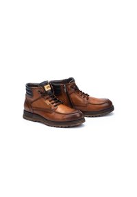 Bottines en cuir brun avec une finition lisse, accents noirs, couture décorative, laçage à l'avant et fermeture éclair sur le côté pour un accès facile.