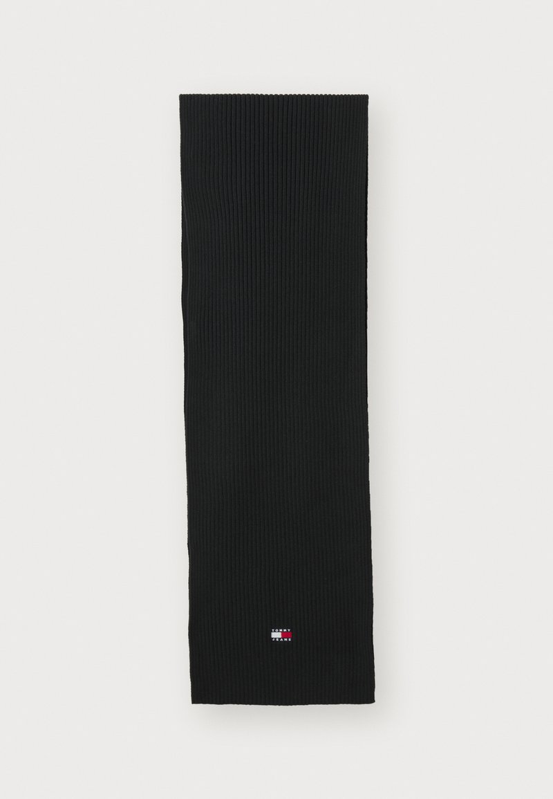Écharpe en tricot côtelé noir avec une petite étiquette logo rouge, blanche et bleue. Forme rectangulaire longue avec un tissu texturé.