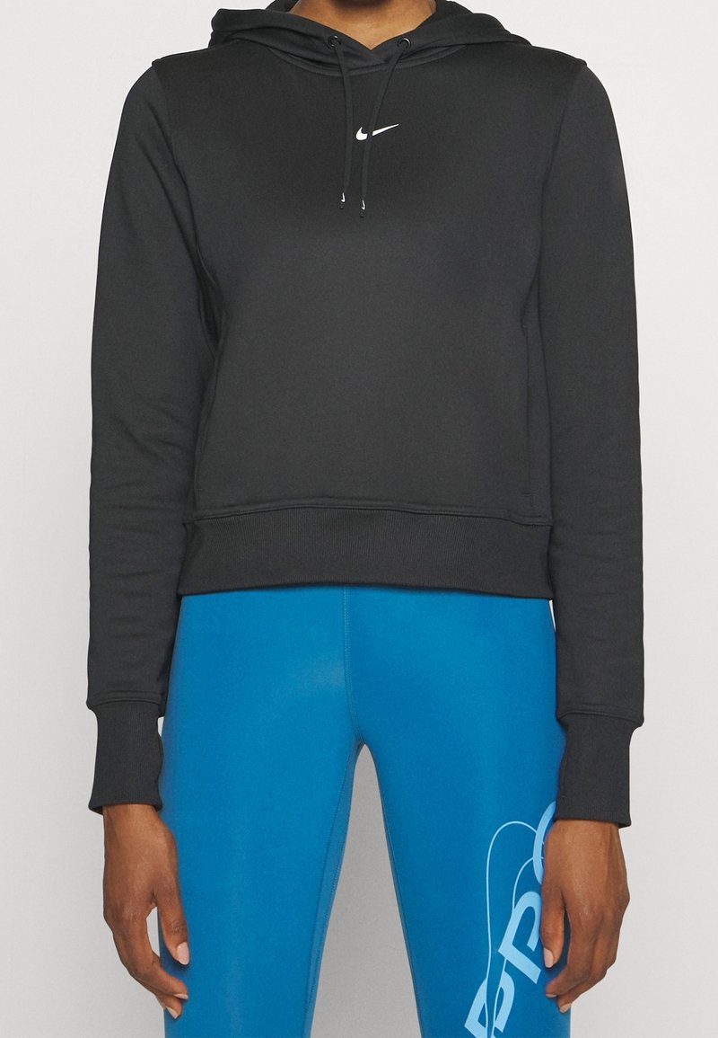 Hoodie cropped nero con cappuccio regolabile e logo Nike bianco, abbinato a leggings blu con una grafica bianca audace sul lato.