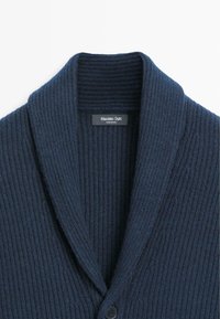Navy blue ribbed cardigan with a wide shawl collar and a single button closure. Material appears soft and textured, label visible inside.