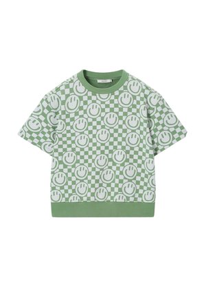 Chemise verte à manches courtes avec motif damier blanc et visages souriants verts répétés, col rond côtelé et ourlet.