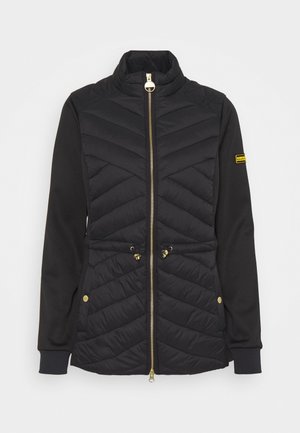 Black quilted jacket with gold zipper, adjustable waist cords, side pockets with gold snaps, and Barbour logo patch on left sleeve.