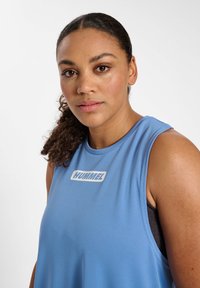 Light blue athletic tank top with a round neckline, sleeveless design, and white "HUMMEL" logo on the front; smooth texture.