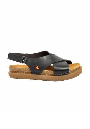 Sandalia negra de cuero con punta abierta, correa trasera ajustable, plantilla de corcho acolchada, suela marrón flexible y pequeño logotipo de flor naranja en el lateral.