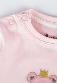 Body neonato rosa chiaro con chiusure a pressione, caratterizzato da un design ricamato di un orso con una corona. Realizzato in cotone morbido, con scollo rotondo.
