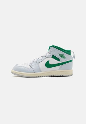 Zapatilla Air Jordan de caña media blanca y verde con el logo de Nike en verde y cuello, cordones blancos y suela color crema sobre un fondo gris liso.