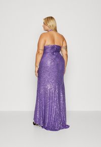 Robe de soirée violette en sequins avec un design sans bretelles, un corsage ajusté et une jupe fluide. Présente un ruché à l'arrière et une silhouette longue jusqu'au sol.