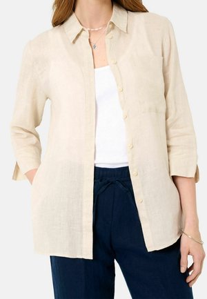 Beige linneskjorta med knappfront, spetsig krage och bröstficka. Har trekvartslånga ärmar och lätt textur.