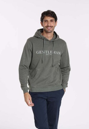 Hoodie vert olive en mélange de coton, avec une poche avant, capuche à cordon de serrage, et texte blanc "GENTLEMAN EST. 90" sur la poitrine.