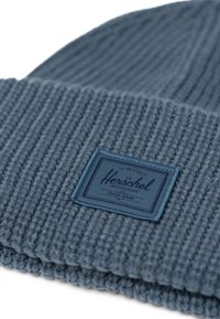 Beanie lavorato a maglia di colore blu scuro con texture a coste, orlo piegato e un'etichetta rettangolare del marchio Herschel cucita sul davanti.