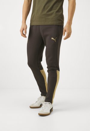 Zwarte en gouden sportbroek met een aansluitend ontwerp, voorzien van zijpanelen in goud en een klein gouden logo op de linker bovenbeen.