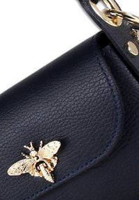 Marine lederen handtas met een gestructureerde afwerking, gekenmerkt door een gouden bijmotief en gouden hardware, samen met stikwerkdetails en een klep-sluiting.