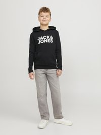 Črna bombažna kapuca z velikim belim logotipom "JACK & JONES", kenguru žep, v kombinaciji s sivo jeans hlačami in belimi supergami.