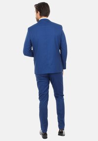 Abito blu realizzato in tessuto morbido, con giacca a un petto e pantaloni slim-fit. Completato con scarpe nere per un aspetto raffinato.