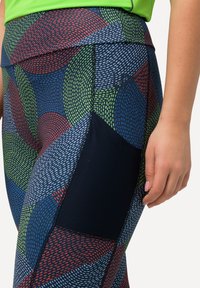 Kleurige leggings met een geometrisch patroon in blauw, rood, groen en zwart, voorzien van een zwarte netzak en een gladde textuur.