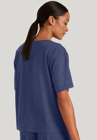 Navyblauwe katoenen T-shirt met korte mouwen, een relaxte pasvorm en platte naaddetails, gezien vanaf de achterkant.