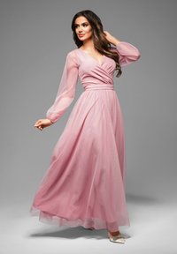 Lång rosa klänning med en åtsittande bodice, V-ringning och flytande kjol. Elastiska, genomskinliga ärmar ger textur och rörelse.