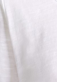 Witte stof met een zachte, fijne textuur en subtiele horizontale strepen. Het materiaal lijkt lichtgewicht en soepel.