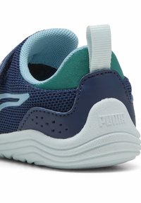 Marinblå idrottssko med mesh-överkropp, teal-accenter, texturerad gummisula och en vit dragflik vid hälen. Har perforerade detaljer.
