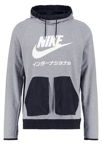 Šedá mikina s kapucí a námořnickými akcenty, se velkým bílým logem a dvěma předními kapsami. Vyrobena z měkkého materiálu s texturovaným povrchem.