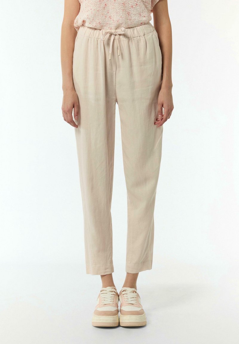 Pantaloni beige, leggeri e dal taglio comodo, con vita elasticizzata e cordoncino regolabile. In abbinamento a delle scarpe da ginnastica eleganti e casual.